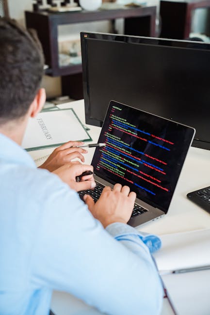 A close-up view of a laptop computer displaying a software development environment with lines of HTML and CSS code, alongside a simple digital calculator application with orange buttons for numerical